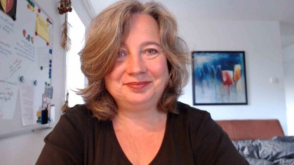 Frances Dahlenburg am Schreibtisch in die Kamera lächelnd.