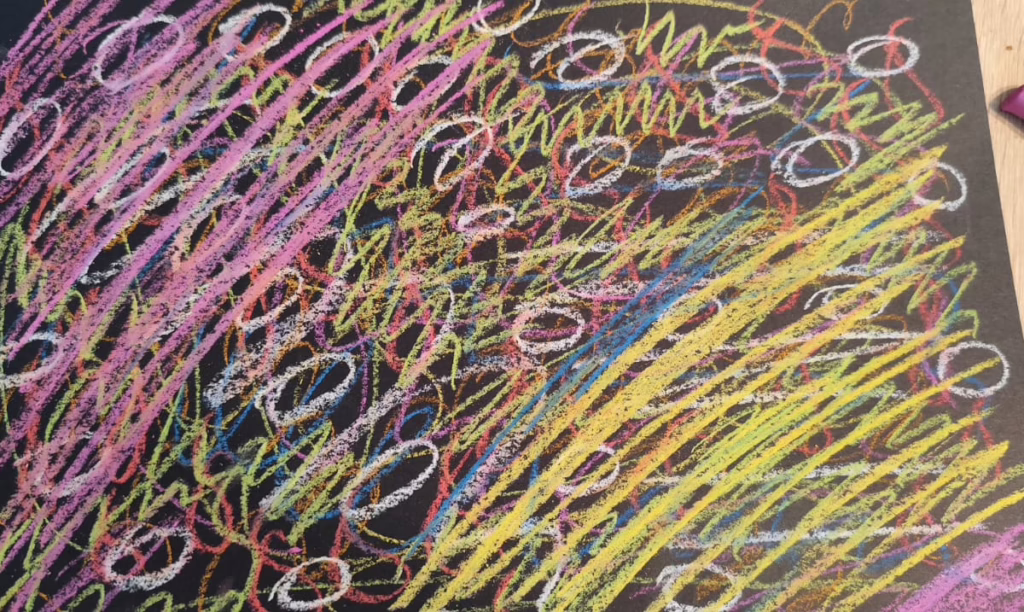 Pastellkreidenlinien, vorwiegend diagonal rosa und gelb auf dunklem Papier, dazwischen kreisförmige Elemente. Teil des Kunsttherapieprozesses im Selbstverfahren, mit dem sich Frances im September 2025 aus toxischen Bindungen löste.