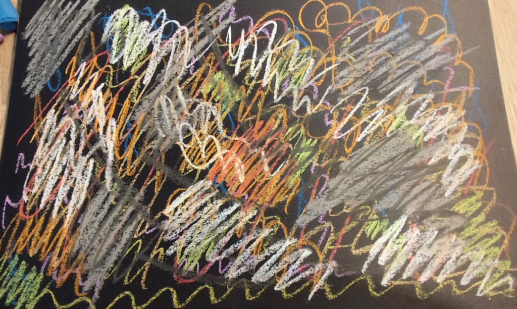 Farbige Pastellkreideflächen auf schwarzem DIN A4 Papier. Das Papier ist fast vollständig bedeckt und es gibt schwarze Linien, die alles unterbrechen. Teil des malenden Transformationsprozesses von Frances im September 2025