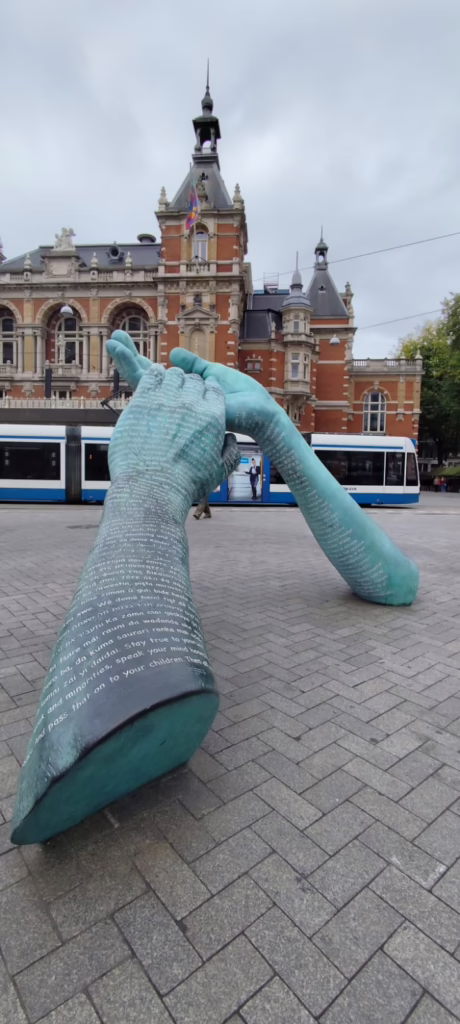 Große Skulptur vor niederländischem Haus: Zwei Hände halten einander. Symbol für Zusammenhalt und versöhnung. Aufgenommen im September 2025 in Amsterdam.