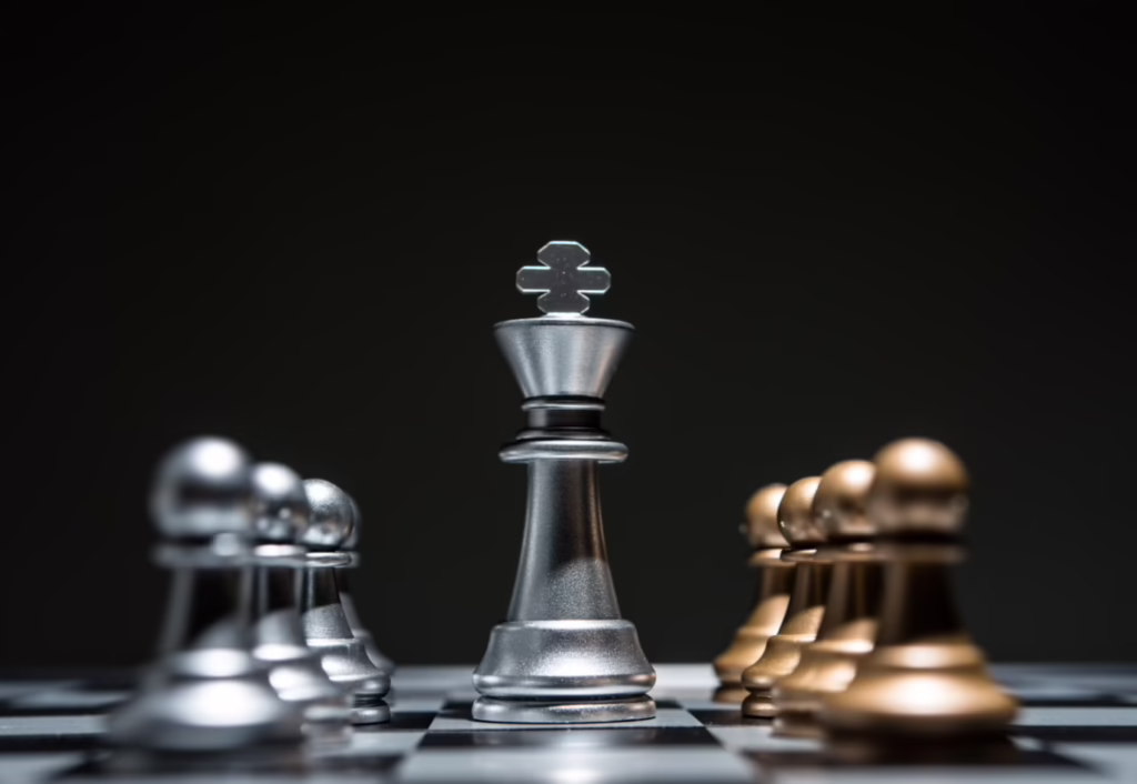 Goldene und silberne Schachfiguren vor schwarzem Grund. Kleine Bauernfiguren rahmen den Weg eines großen silbernen Königs. Die Manipulationstaktik DARVO spielt nicht nach fairen Regeln. Es geht darum, zu gewinnen. Und dabei wird auch nicht vor deiner Wahrnehmung und deiner geistigen Gesundheit Halt gemacht.